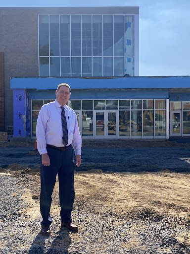 Mr. Miles poses in front of the entrance to the new high school